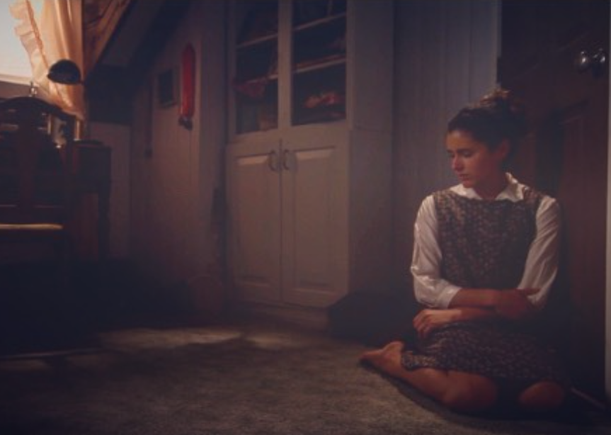A scene from the film "Precarious": a young forlorn woman alone in a room
